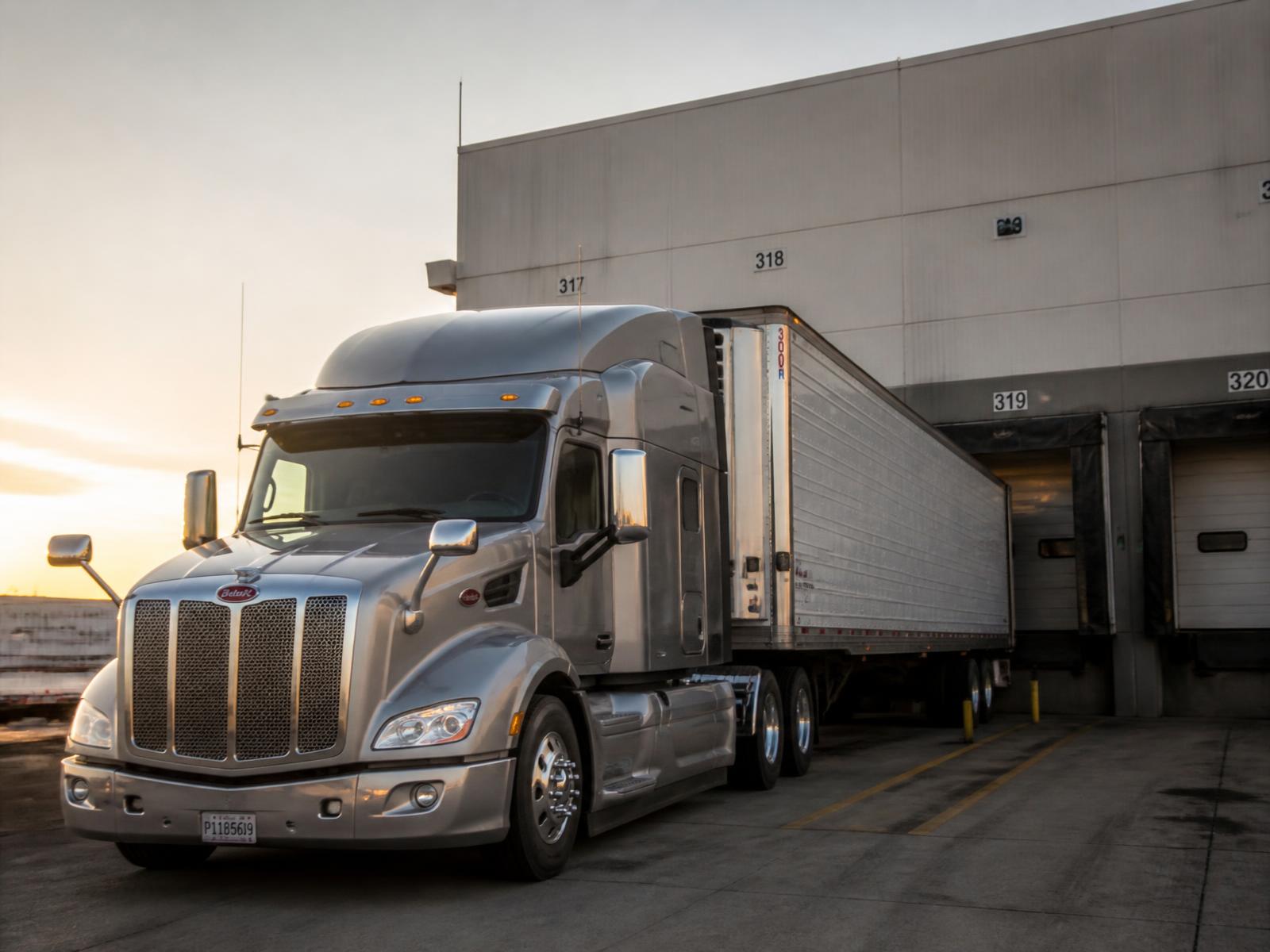 American Peterbilt semi truck at a US distribution center loading dock at dawn